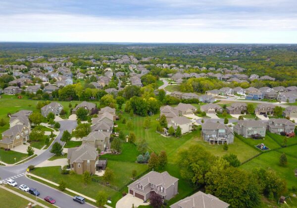 Aerial view of a suburban neighborhood with houses, roads, and lush greenery.