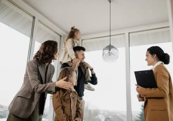 A family with children excitedly tours a modern home guided by a real estate agent.
