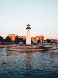 A picturesque lighthouse at sunset by the urban waterfront, offering scenic views.
