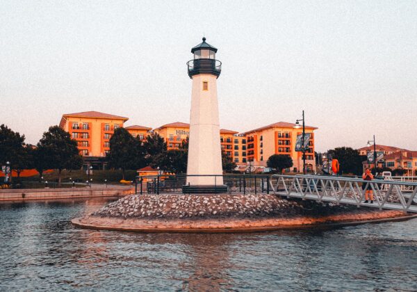A picturesque lighthouse at sunset by the urban waterfront, offering scenic views.