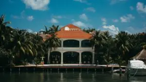 Stunning waterfront resort featuring a yacht and palm trees under a bright summer sky.