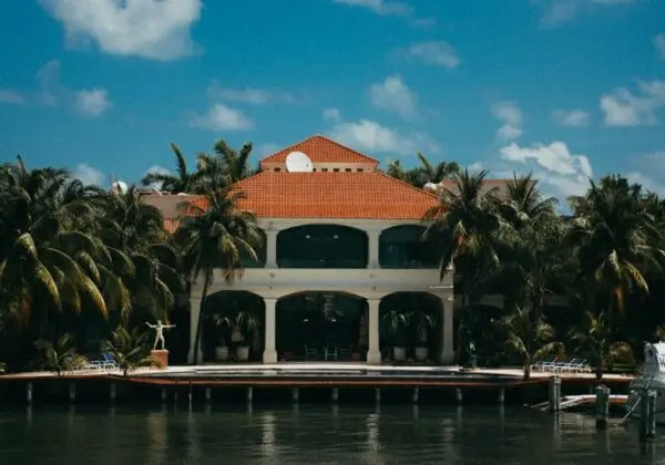 Stunning waterfront resort featuring a yacht and palm trees under a bright summer sky.